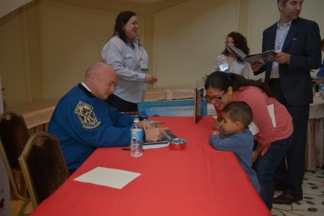 Captain Mark Kelly signs a copy of his book, Mousestronaut, for a young attendee

